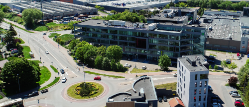 Widok z lotu ptaka na siedzibę PSSE, budynek ze szklaną elewacją, przed nim Rondo Hakenbergera oraz ulice Trzy Lipy i Schuberta